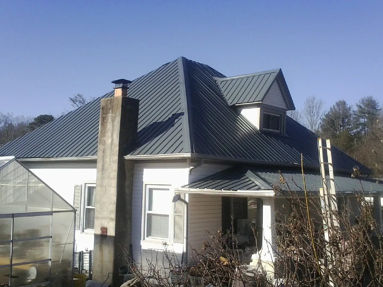Dark blue standing seam metal roof on a white farmhouse with dormer — Slate & Tile Roof Repair by Roofing Brothers in Abell
