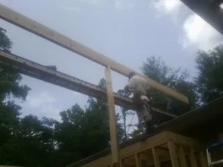 Carpenter setting a ridge beam over a new addition frame — Ice Dam Removal by Roofing Brothers in Abell