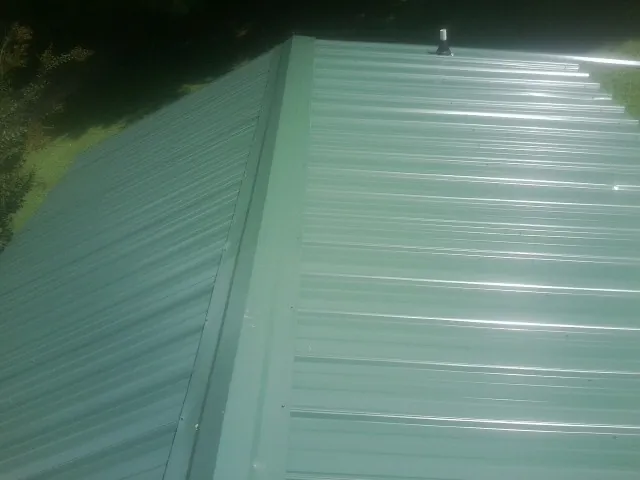 New green metal panels meeting at the ridge of a roof — Flat Roof Repair work by our crew in Abell