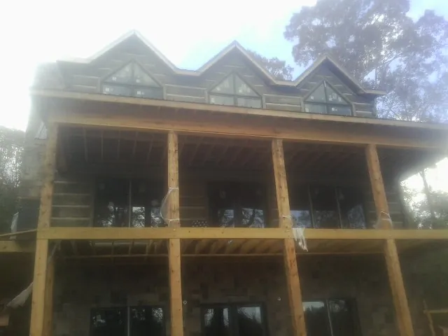 Dormers and porch framing on a large log home under construction — Roof Coating work by our crew in Abell
