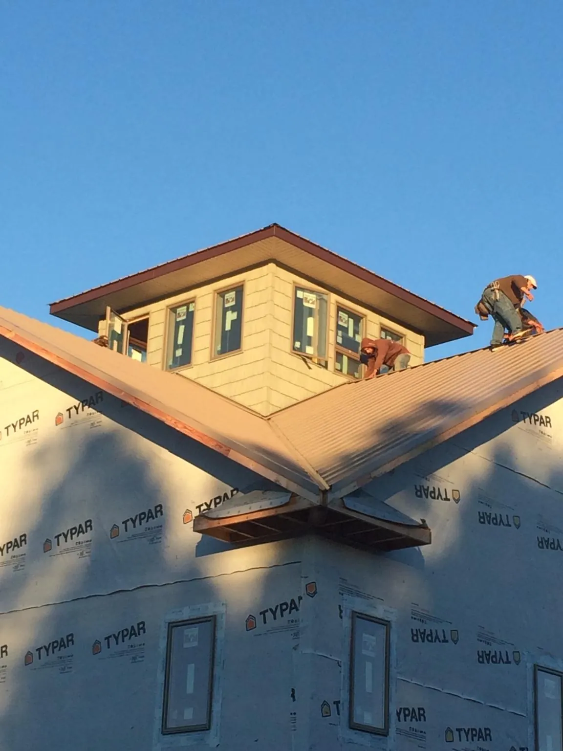 Roofers working around a rooftop cupola on a new metal roof at sunset — Roof Waterproofing in Abell by Roofing Brothers